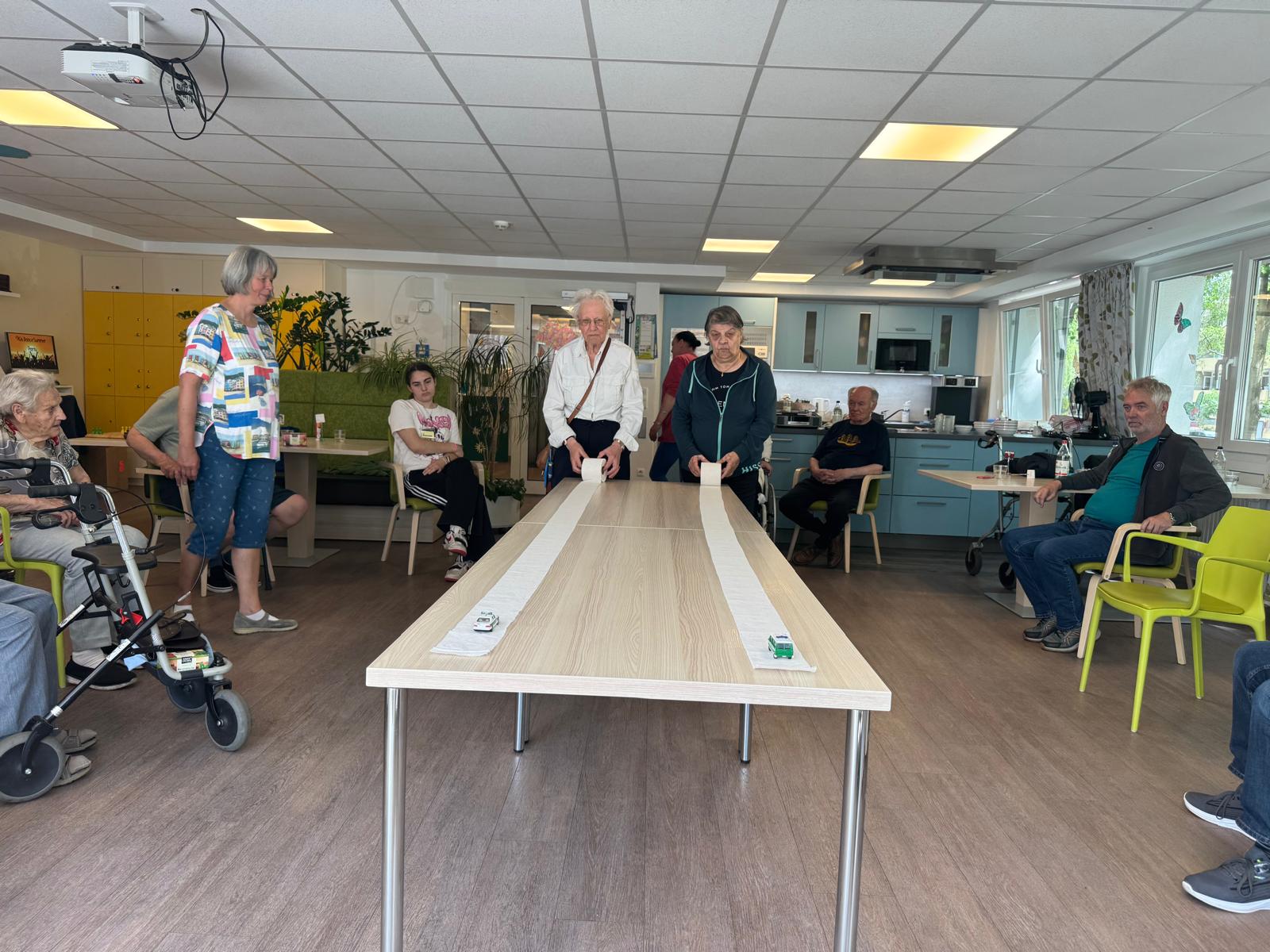 Seniorinnen und Senioren der AWO Tagespflege Mümmelmannsberg nehmen beim Sommerfest begeistert am Autorennen-Spiel teil.